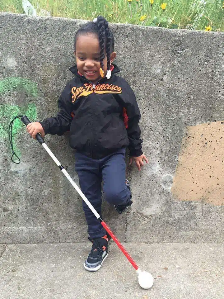 Young girl with cane leaning against a wall