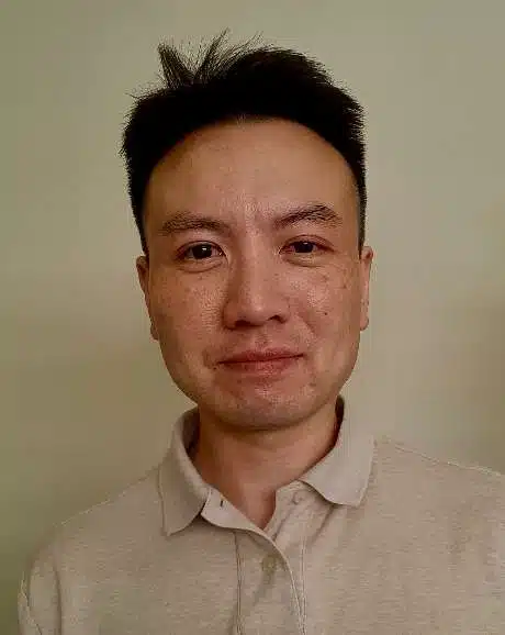 middle-aged Man of Asian descent is smiling and looking into the camera, wearing a cream colored polo.